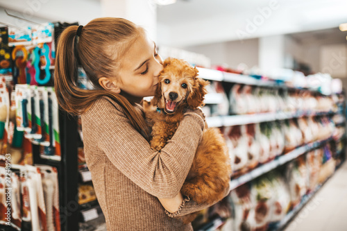 Cute girl with her poodle puppy in pet shop. photo