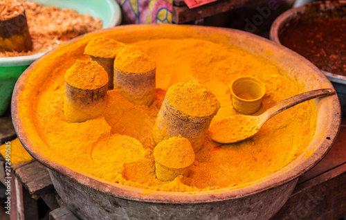 Makassar, Sulawesi, Indonesia - February 28, 2019: Terong Street Market. Closeup of pot filled with orange turmeric powder. photo