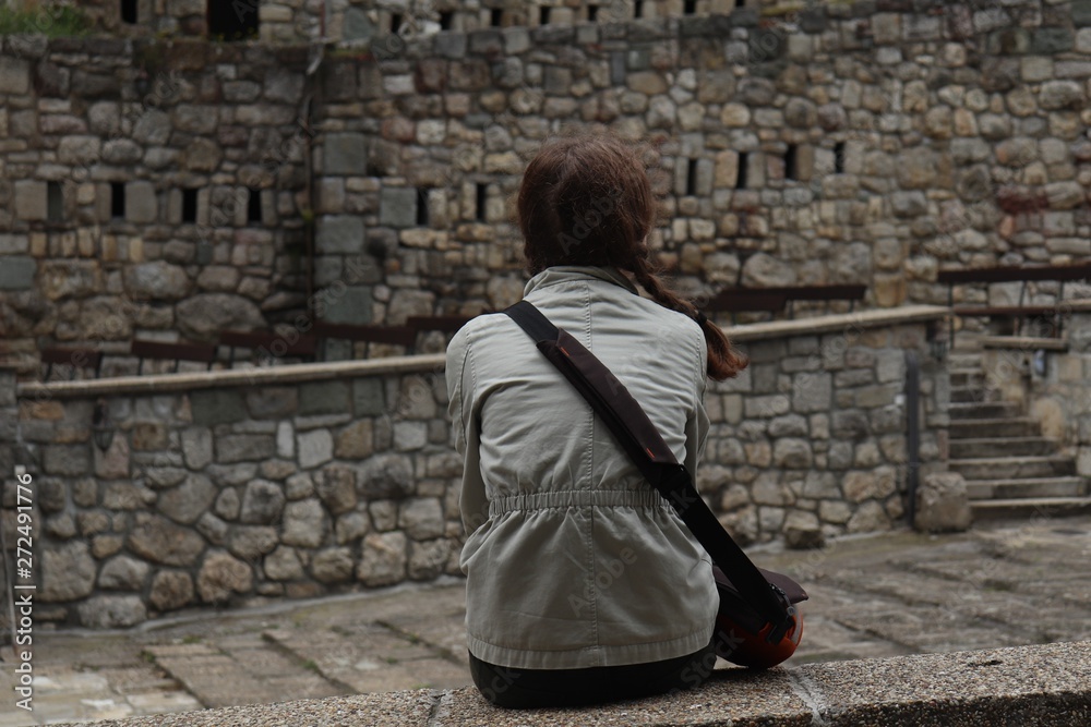 The girl sits on the wall in the castle
