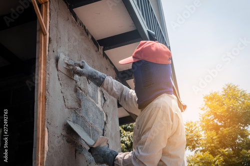 Construction workers plastering building wall using cement plaster