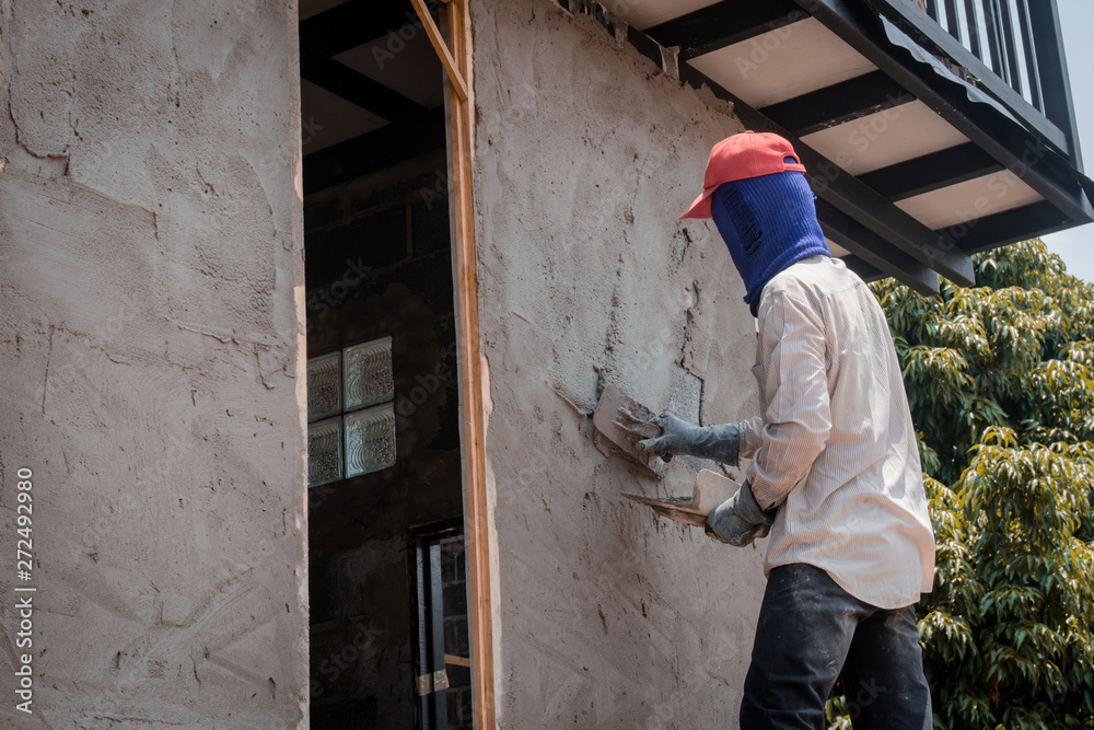 Construction workers plastering building wall using cement plaster Construction workers plastering building wall using cement plaster