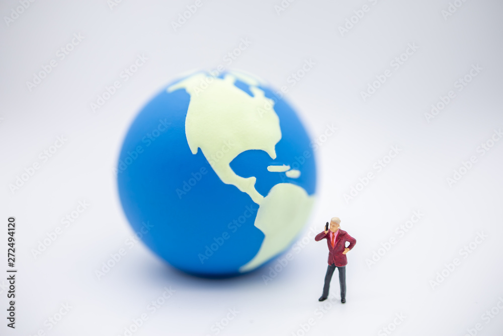 Global Communication concept. Close up of businessman miniature figure standing and make a phone call with mini world ball on white background.