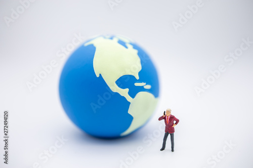 Global Communication concept. Close up of businessman miniature figure standing and make a phone call with mini world ball on white background.