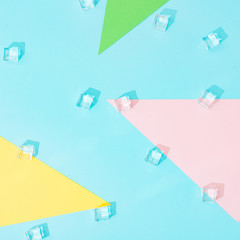 Creative summer background composition with ice cubes and colorful paper shapes. Minimal top down.
