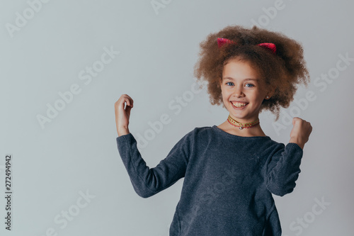 Headshot Portrait of happy girl  with curly hair  smiling looking at camera. gray background. © Nana_studio
