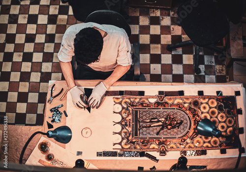 Process of restouration antoque stained glass by expirienced restorer at his workshop. Top view, checkered floor at background. photo