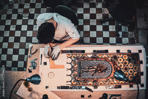 Process of restouration antoque stained glass by expirienced restorer at his workshop. Top view, checkered floor at background. photo