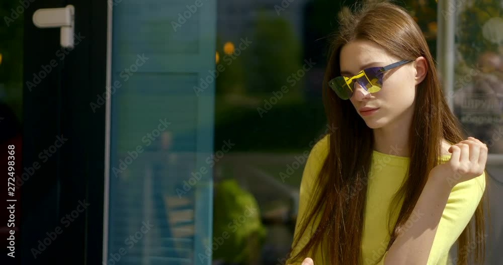 cheerful young woman with trendy sunglasses is drinking coffee in street cafe, looking on phone cheerful young woman with trendy sunglasses is drinking coffee in street cafe, looking on phone