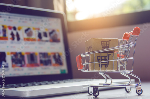 Shopping online concept - Parcel or Paper cartons with a shopping cart logo in a trolley on a laptop keyboard. Shopping service on The online web. offers home delivery