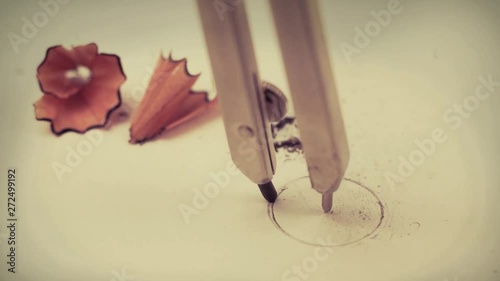 Closeup macro detail of drawing a circle with a precision geometry pencil compass on mathematics notebook paper with sharpening wood shavings with copyspace - Concept of school education, learning