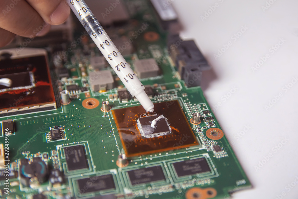Technician applying thermal paste with syringe on the GPU processor on  motherboard laptop Stock Photo | Adobe Stock