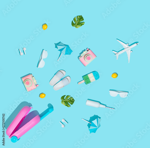 Summer vacation concept with suitcase and beach items on pastel blue background. Flat lay. Minimal summer travel background.