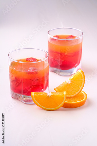 Jelly dessert with strawberries in drink glass with orange slices nearby