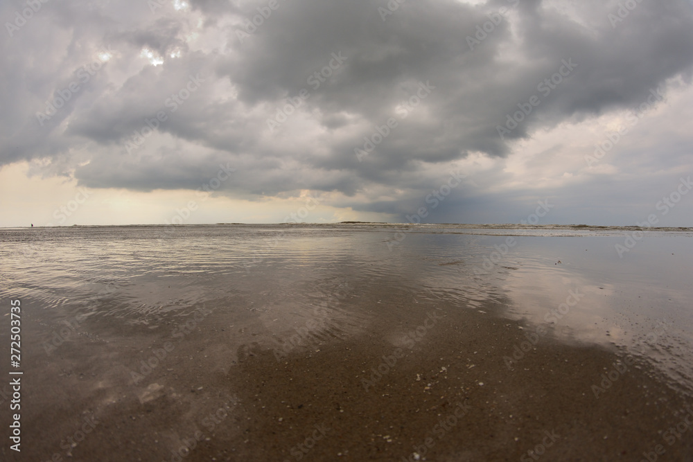 Plażą nad morzem w pochmurny dzień pod niebem z chmurami. Plażą nad morzem w pochmurny dzień pod niebem z chmurami.
