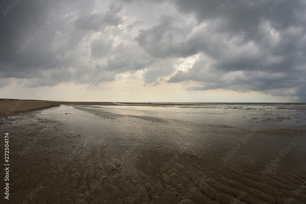 Plażą nad morzem w pochmurny dzień pod niebem z chmurami. Plażą nad morzem w pochmurny dzień pod niebem z chmurami.