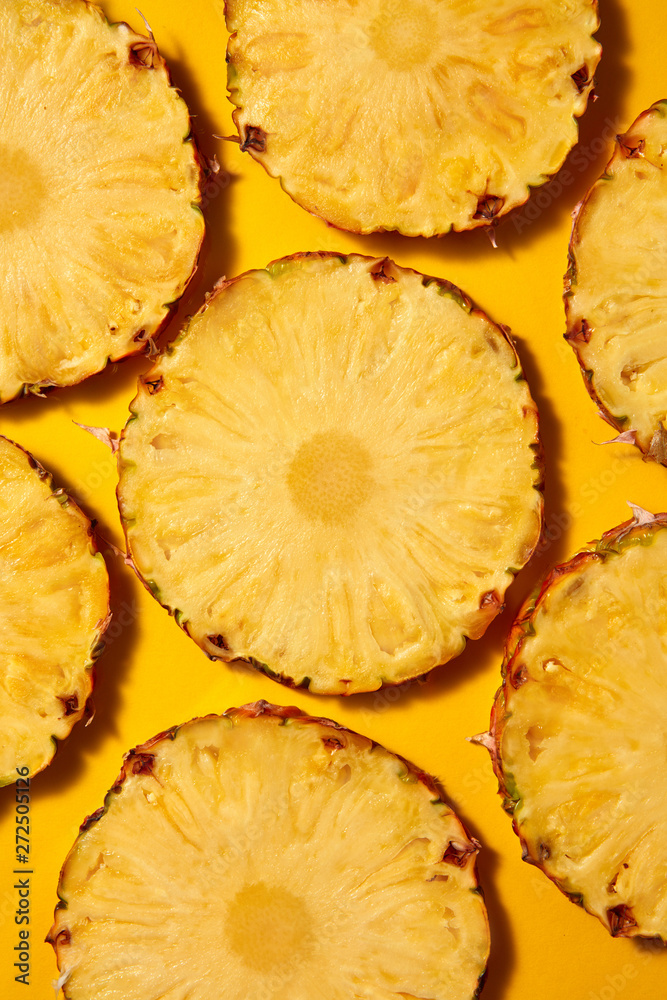 Flat lay background of round slices of juicy ripe pineapple on a Flat lay background of round slices of juicy ripe pineapple on a