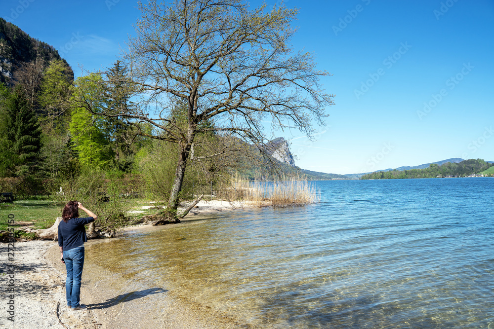 Junge Frau steht an einem See im Salzburger Land