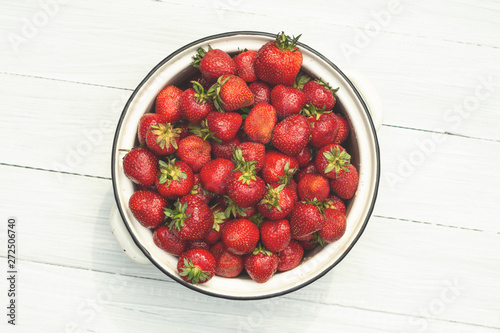 Metal bowl with strawberries on a white wooden table