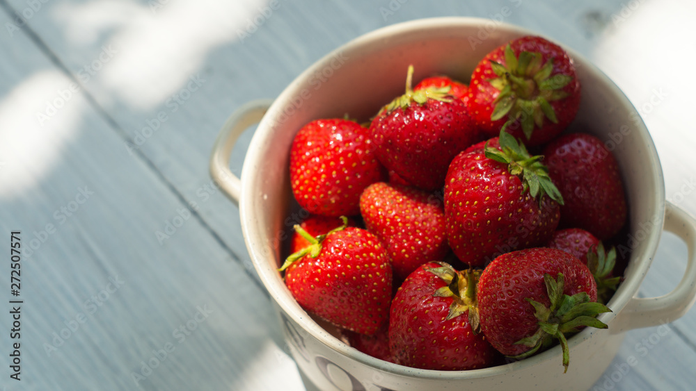 Ripe strawberries in a bowl on the white wooden table Ripe strawberries in a bowl on the white wooden table