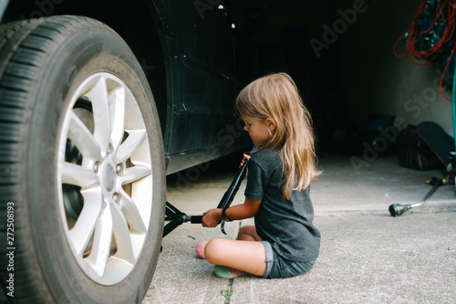 child changes tire on car