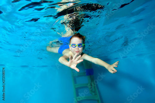 Sporty little boy dives to the bottom of the swimming pool, arms outstretched. Portrait. Close up. Underwater photography. Horizontal orientation