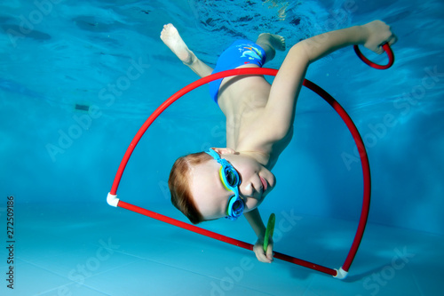A little boy is playing fun, tumbling underwater at the bottom of the pool. Dancing underwater. Creative. Open his eyes. Portrait. Underwater photography. Horizontal orientation of the image photo