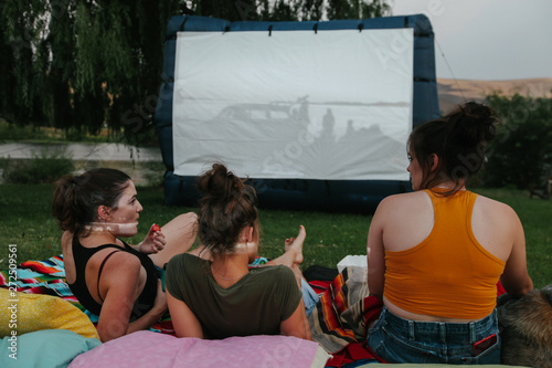 friends and family enjoy watching outdoor movie in yard