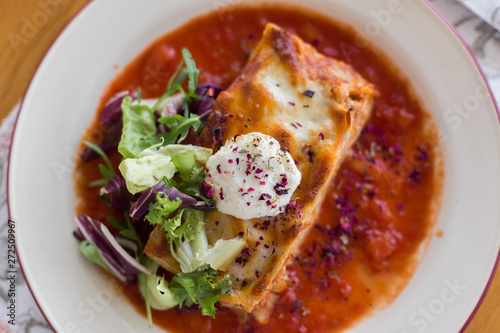 Tasty delicious italian dish lasagna with tomato sauce and cream cheese with green salat. Food, tasty dinner concept