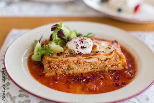 Tasty delicious italian dish lasagna with tomato sauce and cream cheese with green salat. Food, tasty dinner concept