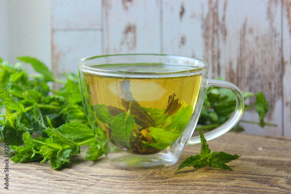 Natural mint tea and fresh mint leaves on wooden rustic background Natural mint tea and fresh mint leaves on wooden rustic background