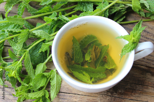 Natural mint tea and fresh mint leaves on wooden rustic background