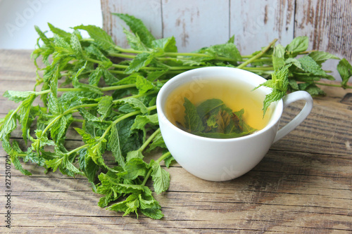 Natural mint tea and fresh mint leaves on wooden rustic background