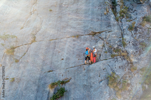 Senior man and young woman climbing a big rock wall.