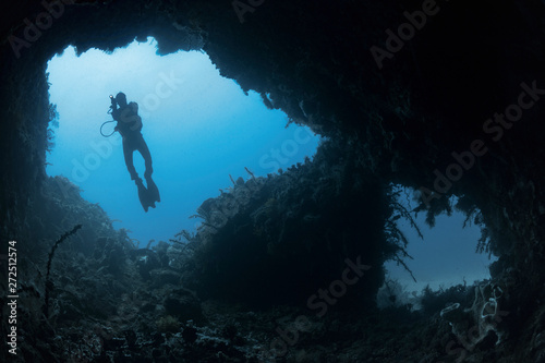 Silhouetted Diver Shines Torch Into Cave photo