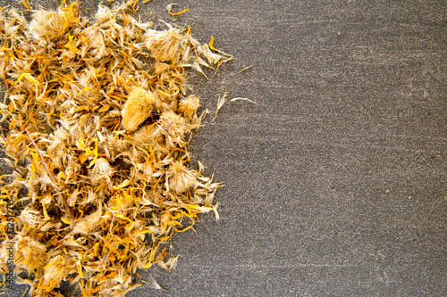 Dried yellow Arnica Flowers  on gray / grey slate background photo