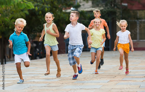 Group of positive children running together in town on summer