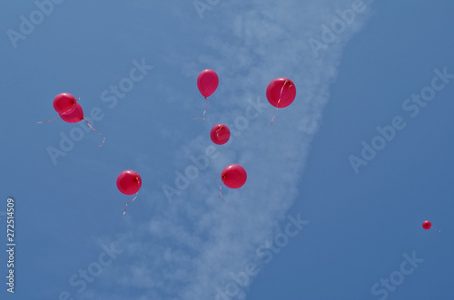 8 red party balloons floating high in blue sky