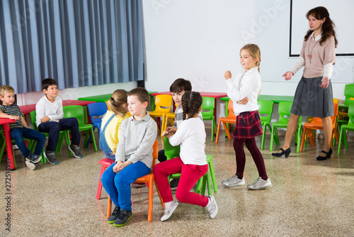 Fototapeta Naklejka Na Ścianę i Meble -  Kids and teacher playing musical chairs