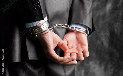 Cropped image of male hands in handcuffs behind his back © BillionPhotos.com