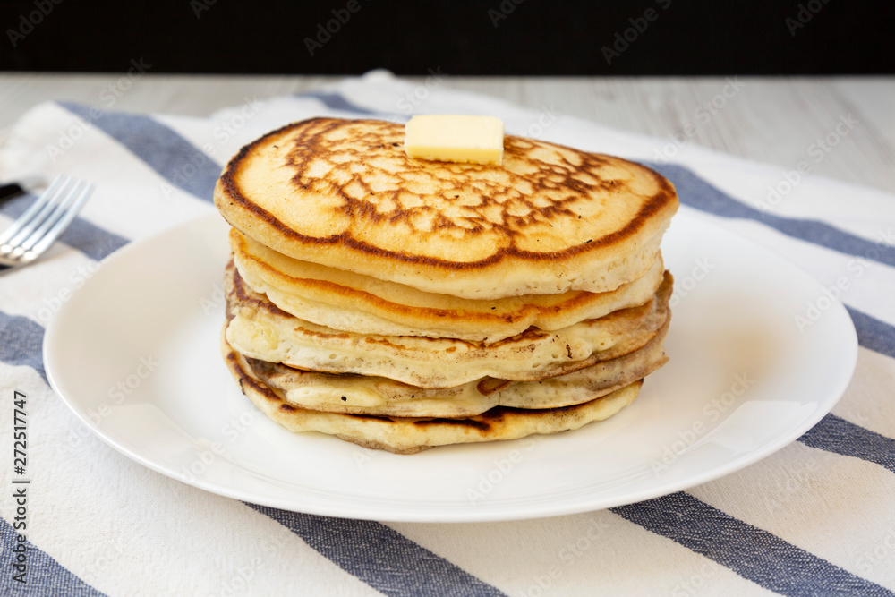 Homemade pancakes with butter on a white plate, side view. Close-up.