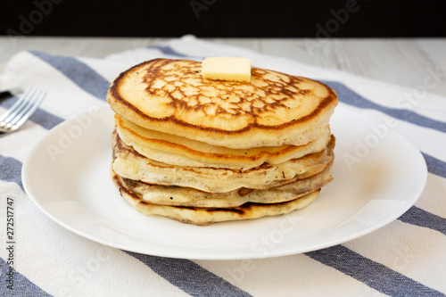 Homemade pancakes with butter on a white plate, side view. Close-up.