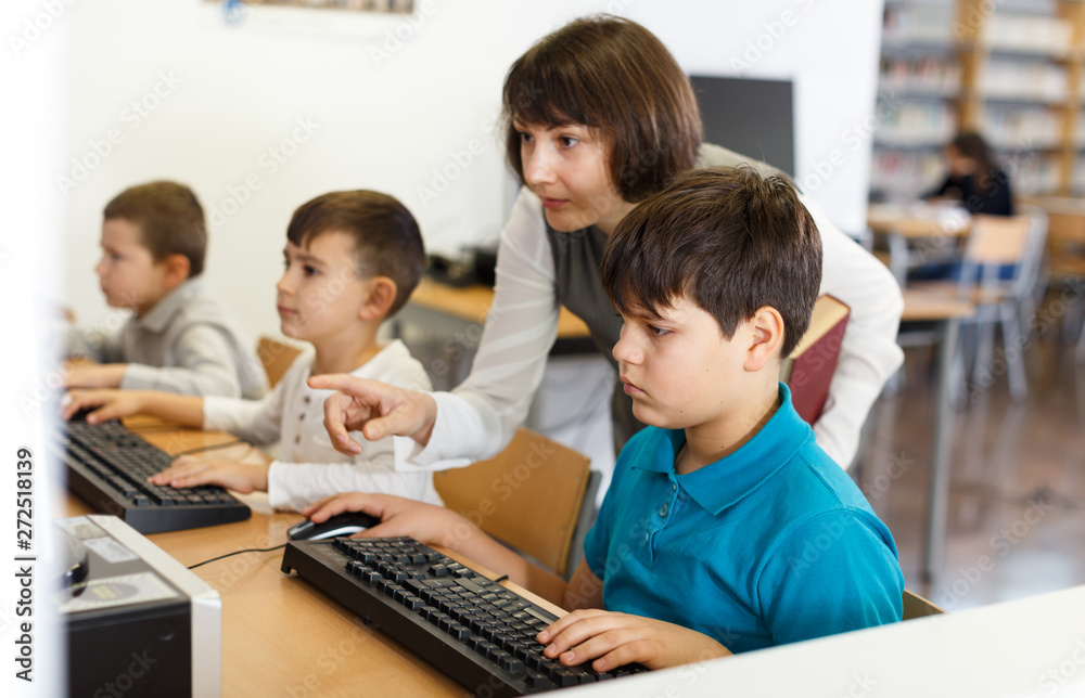 Female teacher working with pupil in computer class