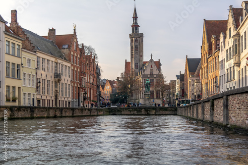 View to Jan van Eyckplein (Jan van Eyck Square) viewed from a nearby canal with Flemish painter Jan van Eyck monument and The Poortersloge (Burgher’s Lodge) building.