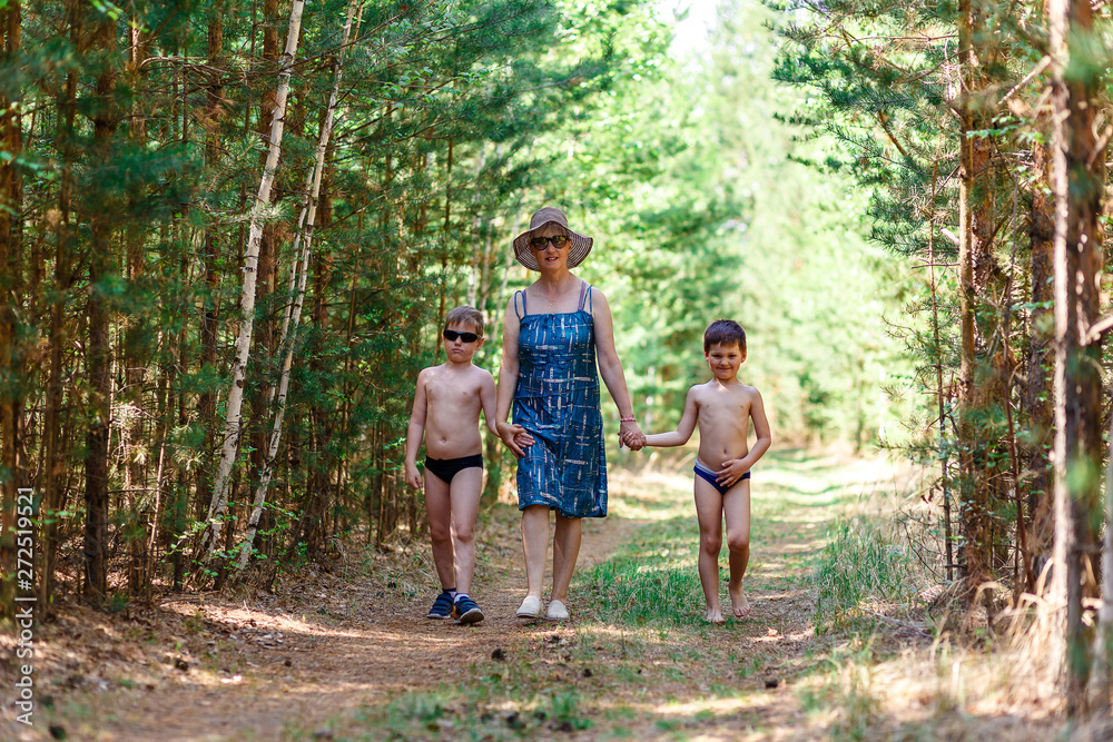 Young grandmother walks in the woods with two grandchildren Young grandmother walks in the woods with two grandchildren