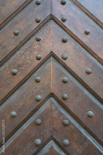 Background of wooden planks folded in the direction of the arrow up, stitched with black metal bolts with a carved head