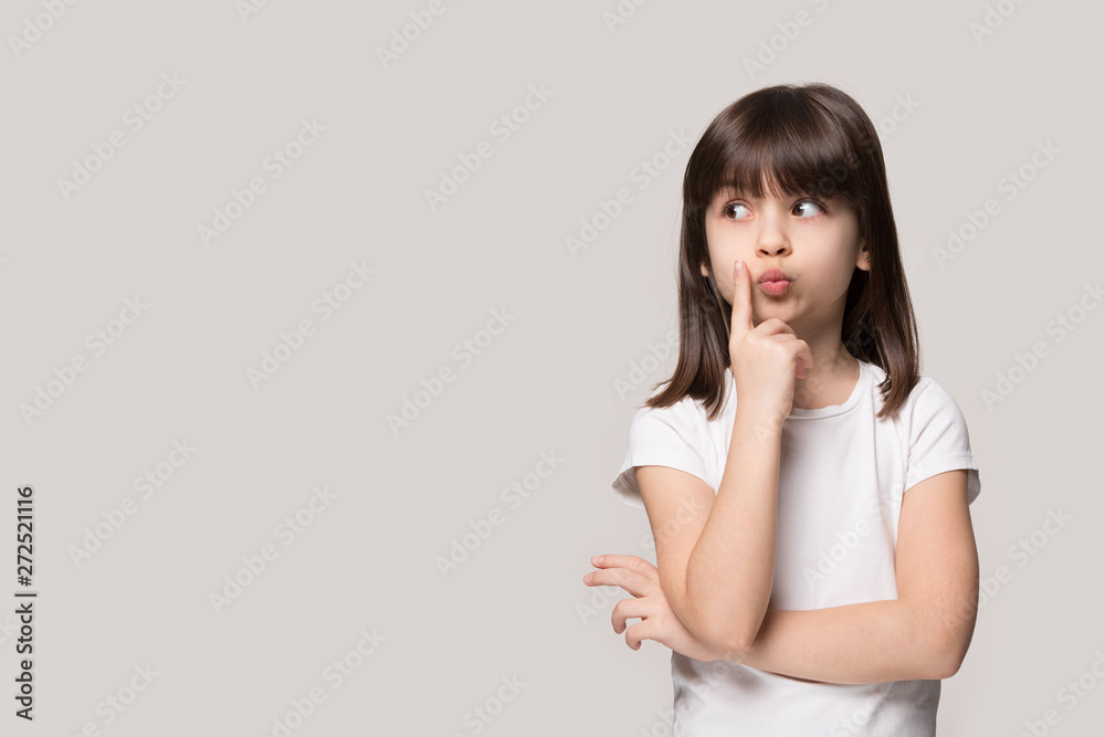Thoughtful little girl looking away thinking isolated on grey background Thoughtful little girl looking away thinking isolated on grey background