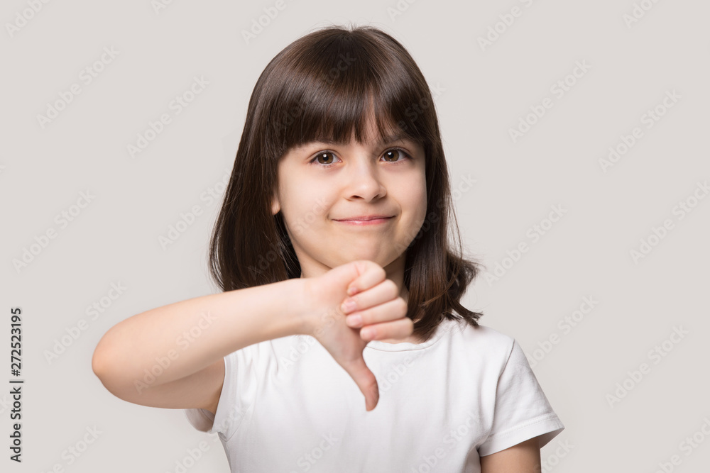 Little girl looking at camera showing thumb down studio shot Little girl looking at camera showing thumb down studio shot