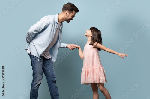 Father and little daughter holding hands dancing waltz studio shot