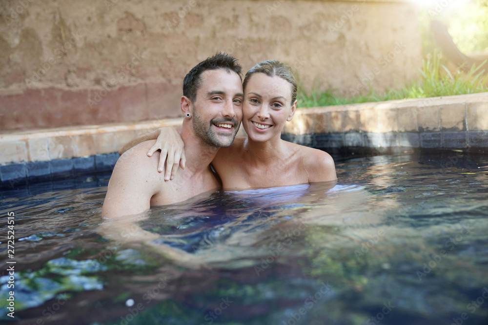 Cheerful couple in Moroccan swimming pool smiling at camera Cheerful couple in Moroccan swimming pool smiling at camera