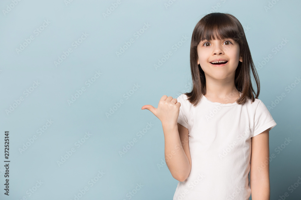 Stunned little girl looks at camera point finger on copyspace Stunned little girl looks at camera point finger on copyspace